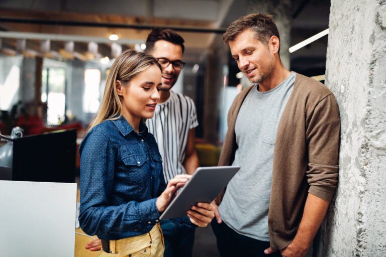 Drei Fachleute stehen zusammen und besprechen Unterlagen auf einem Tablet