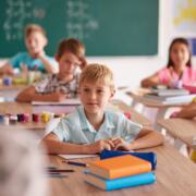 Kinder sitzen an ihren Pulten in einem hellen Klassenzimmer und arbeiten konzentriert